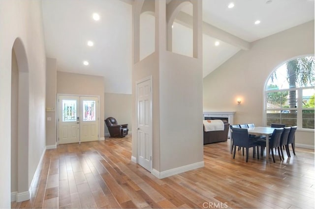 dining area with light wood-type flooring, baseboards, high vaulted ceiling, and beamed ceiling