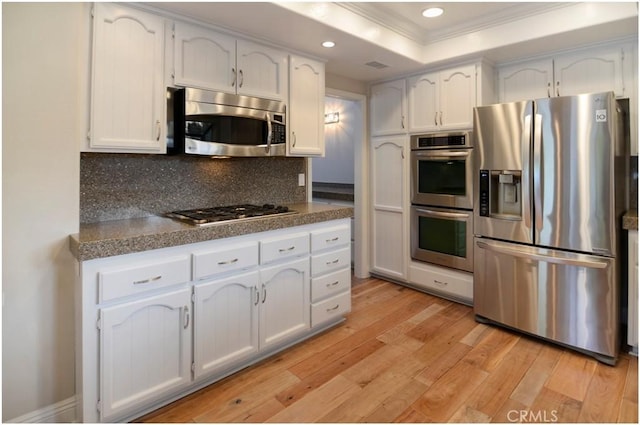 kitchen featuring stainless steel appliances, a tray ceiling, and white cabinetry