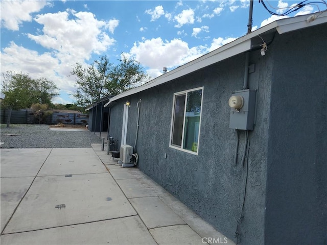 view of property exterior with fence, a patio, and stucco siding