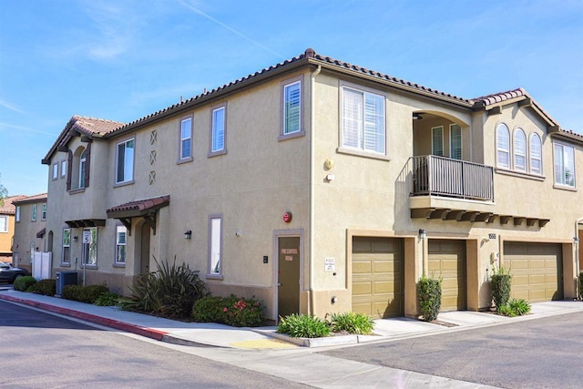 view of front facade featuring a tiled roof, central AC unit, a garage, and stucco siding