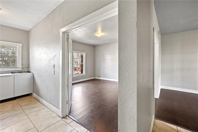 interior space with white cabinetry, baseboards, a wealth of natural light, and a textured wall