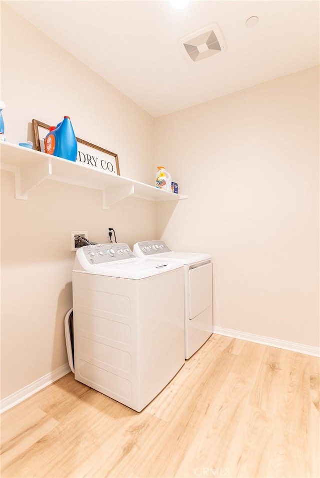 washroom with baseboards, laundry area, wood finished floors, and washer and dryer