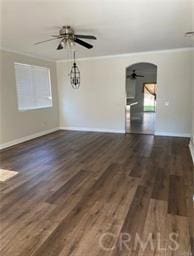 unfurnished room featuring a ceiling fan, arched walkways, dark wood finished floors, and ornamental molding