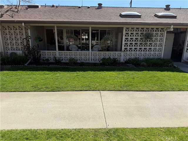 exterior space featuring a shingled roof and a yard