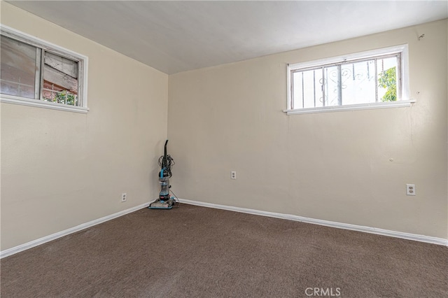 spare room featuring baseboards and dark colored carpet