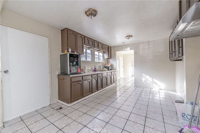 kitchen featuring dark brown cabinets, extractor fan, light tile patterned flooring, and light countertops