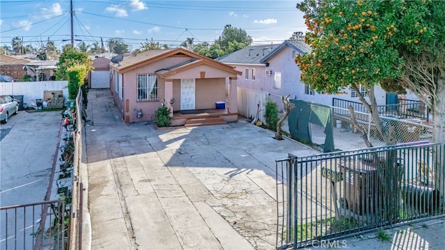 bungalow-style home with a fenced front yard, driveway, and stucco siding