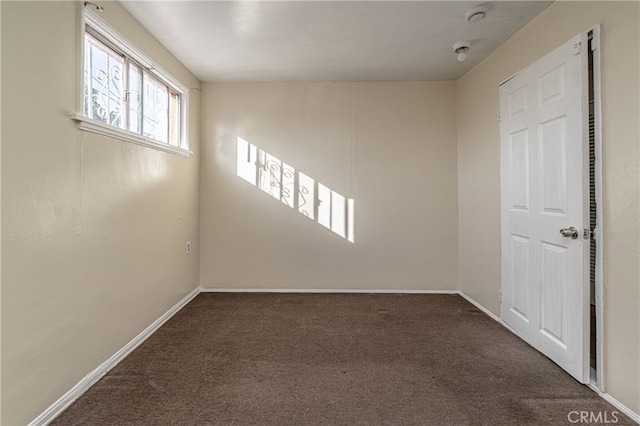 unfurnished room with dark carpet and baseboards