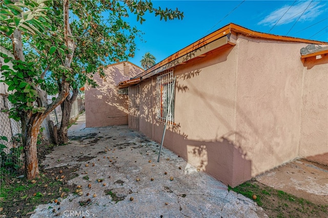 view of side of property featuring fence and stucco siding