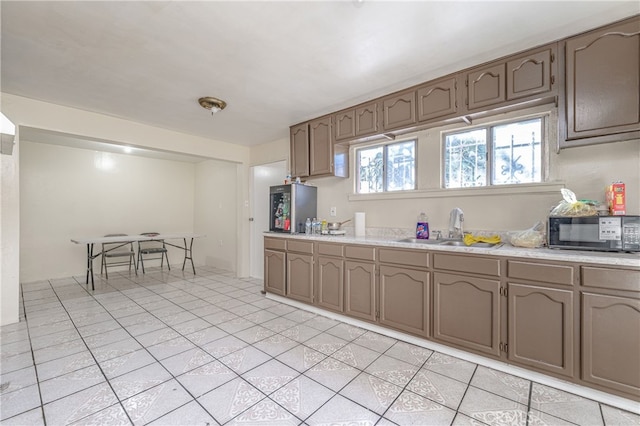 kitchen featuring light tile patterned floors, black microwave, light countertops, and a sink