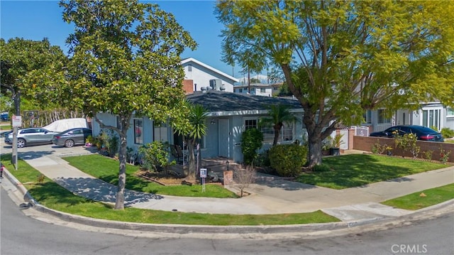 view of property hidden behind natural elements with a front lawn and fence