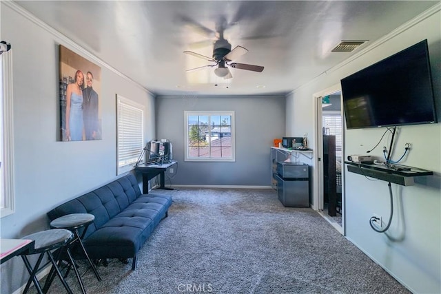 living area with baseboards, a ceiling fan, carpet flooring, and crown molding