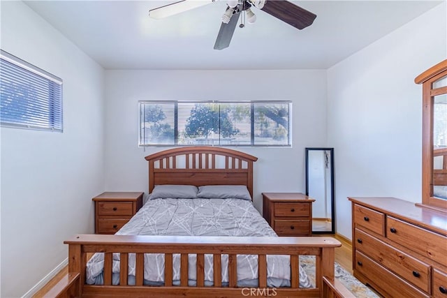 bedroom with light wood-type flooring, multiple windows, and a ceiling fan