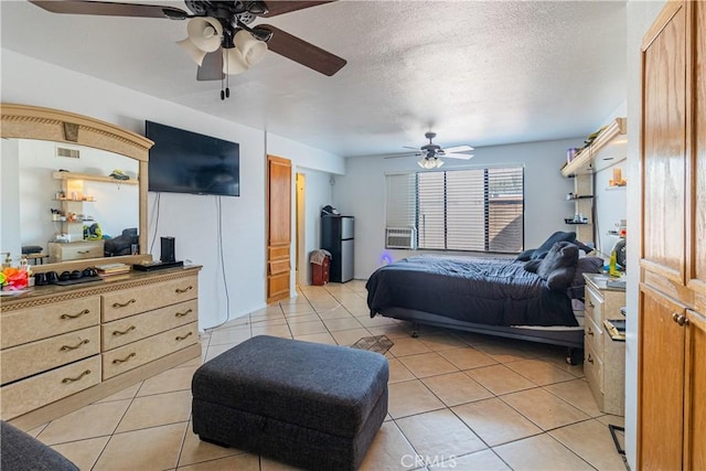 bedroom with visible vents, a textured ceiling, freestanding refrigerator, light tile patterned floors, and ceiling fan