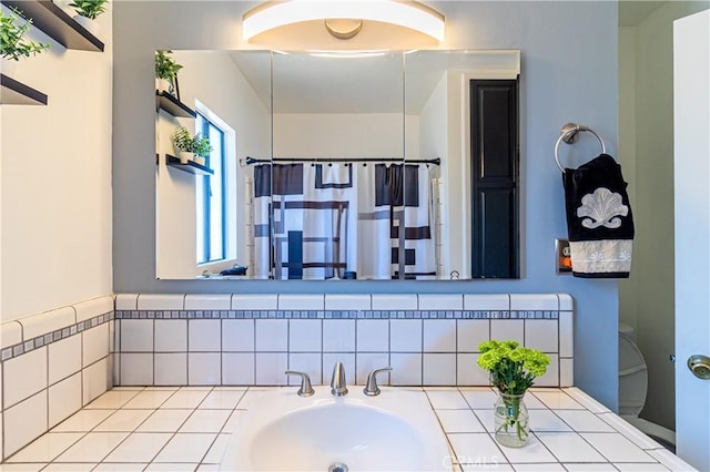 bathroom with curtained shower, toilet, and a sink