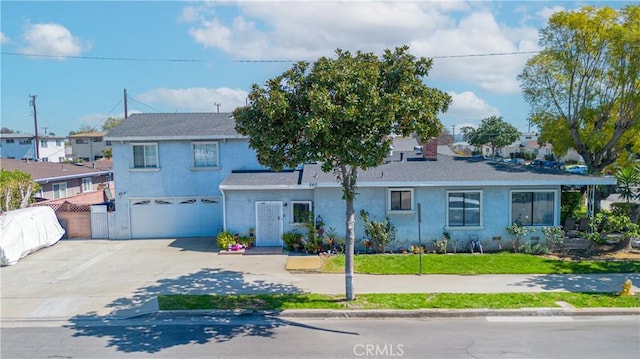 traditional-style home featuring a front yard, fence, an attached garage, stucco siding, and concrete driveway