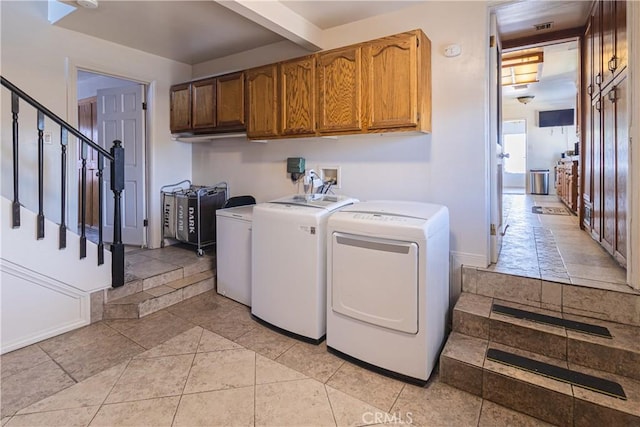 clothes washing area featuring washer and dryer, cabinet space, visible vents, and baseboards