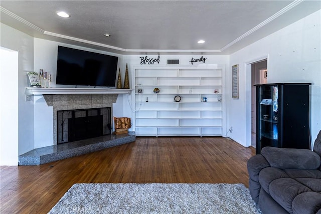 living area with visible vents, a fireplace, crown molding, and wood finished floors