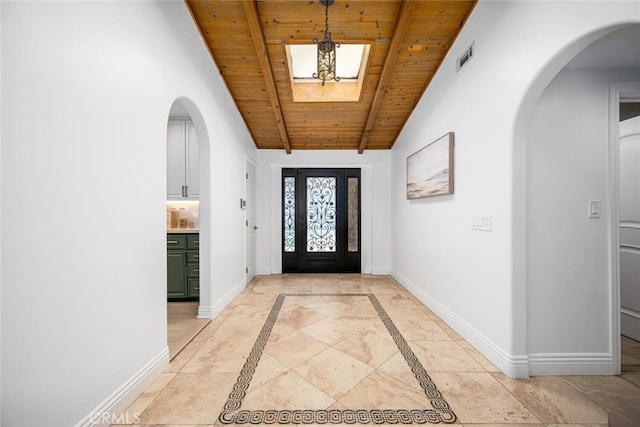 foyer featuring arched walkways, lofted ceiling with beams, wooden ceiling, and baseboards