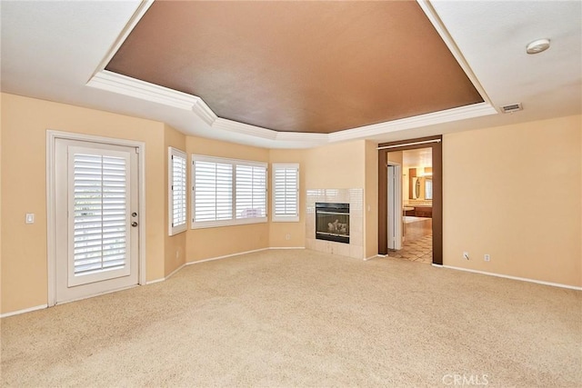 unfurnished living room featuring light carpet, a fireplace, visible vents, baseboards, and a tray ceiling