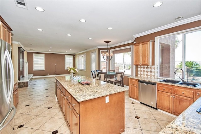 kitchen featuring stainless steel appliances, hanging light fixtures, a kitchen island, a sink, and light stone countertops