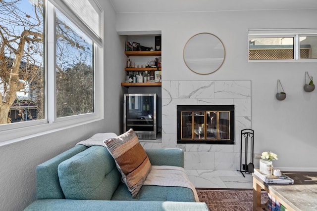 living area featuring marble finish floor, wine cooler, and a premium fireplace