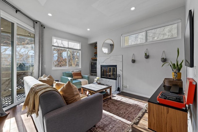 living area featuring recessed lighting, a fireplace, baseboards, and wood finished floors