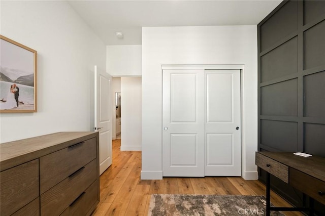 bedroom featuring light wood-type flooring, a closet, and baseboards