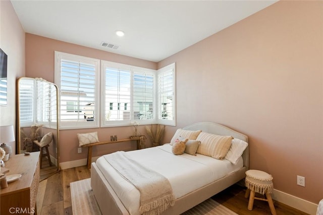 bedroom with baseboards, visible vents, and light wood finished floors