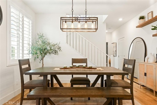 dining space featuring light wood-style floors, stairs, baseboards, and a wealth of natural light