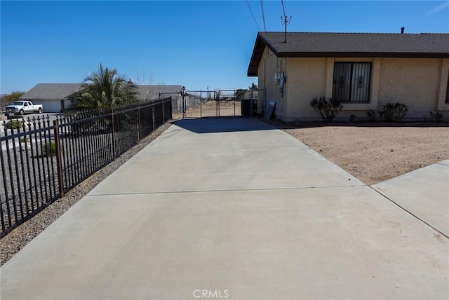 view of home's exterior featuring driveway, stucco siding, and fence
