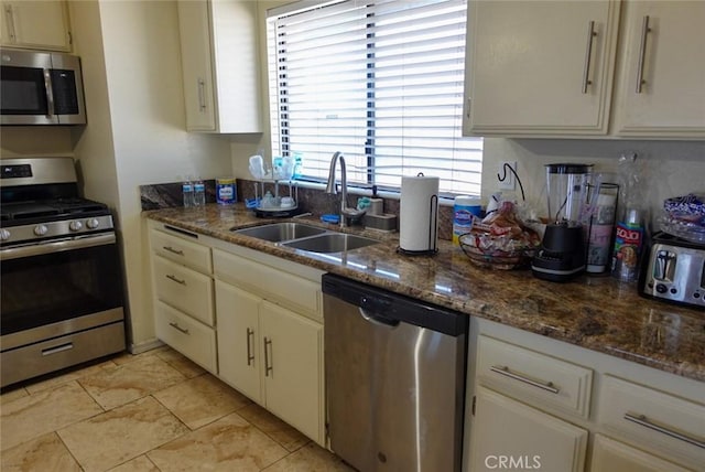 kitchen featuring stainless steel appliances, a sink, and dark stone countertops