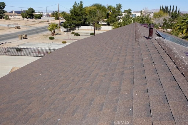 exterior view of fence, a shingled roof, and a chimney