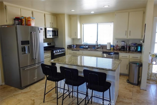 kitchen featuring stainless steel appliances, a sink, light stone counters, a center island, and recessed lighting