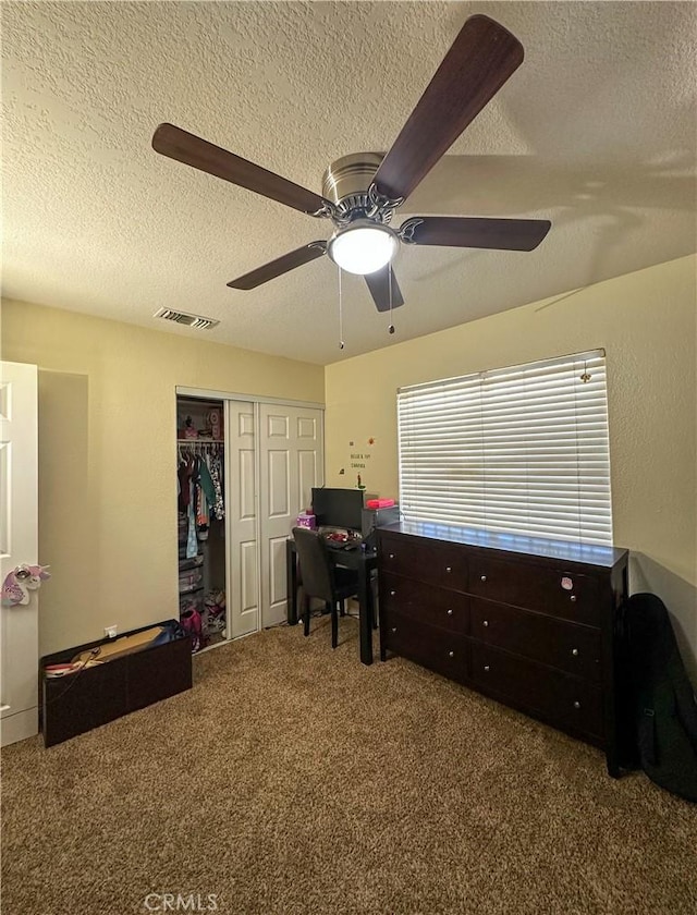 carpeted office with a textured ceiling and a ceiling fan