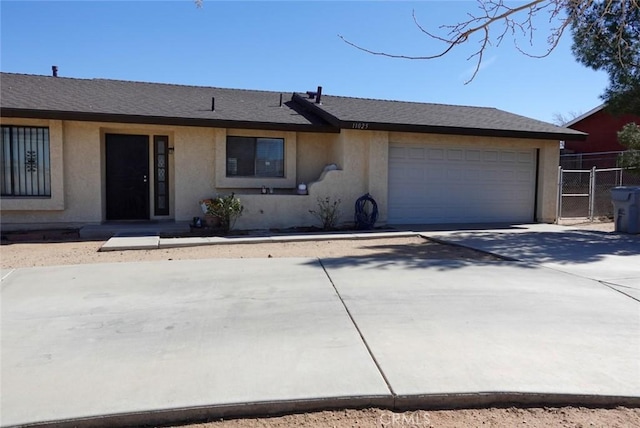 single story home featuring stucco siding, a shingled roof, concrete driveway, an attached garage, and fence