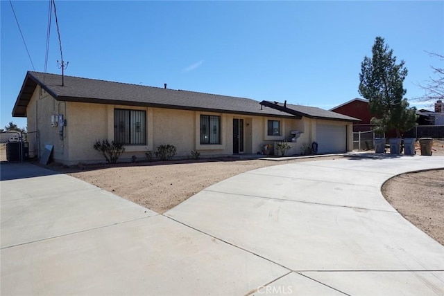 single story home featuring concrete driveway, a garage, fence, and stucco siding