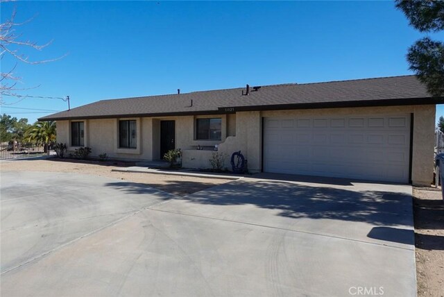 single story home featuring concrete driveway, stucco siding, and a garage