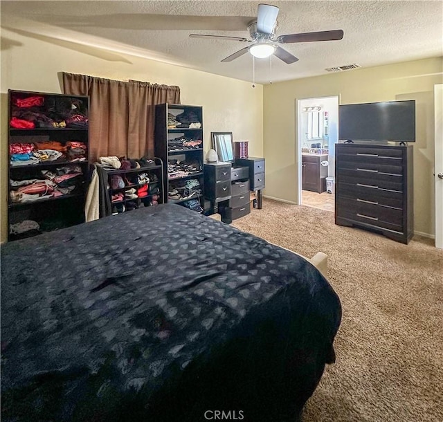bedroom featuring carpet floors, a textured ceiling, ensuite bath, and ceiling fan