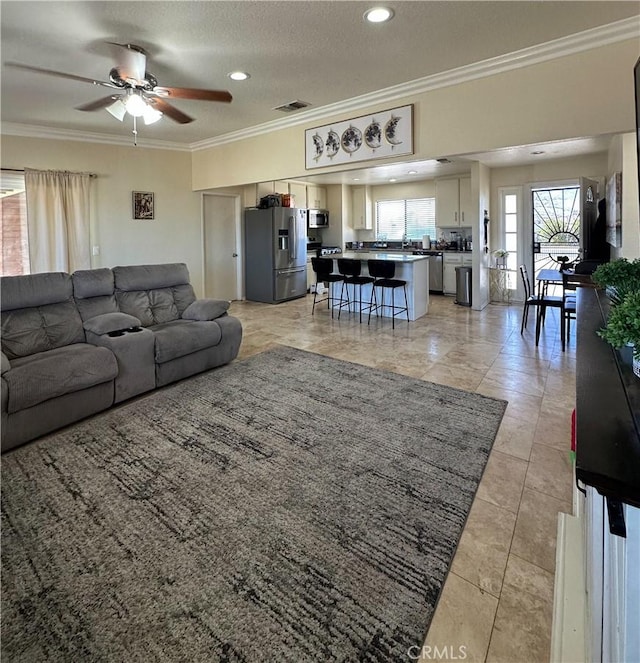 living area with ornamental molding, ceiling fan, recessed lighting, a textured ceiling, and light tile patterned flooring