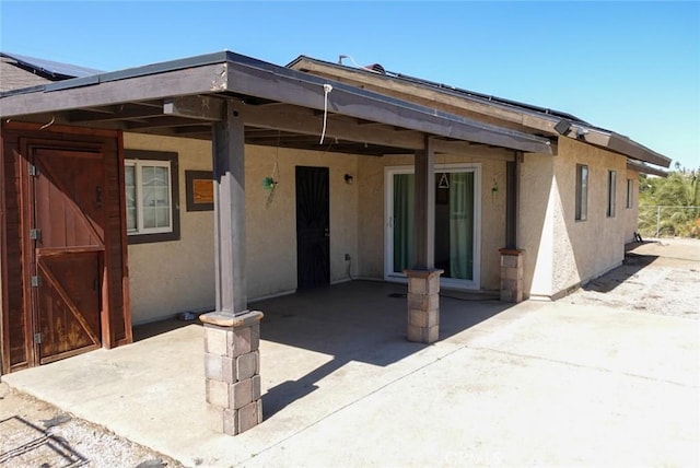rear view of house featuring stucco siding and a patio