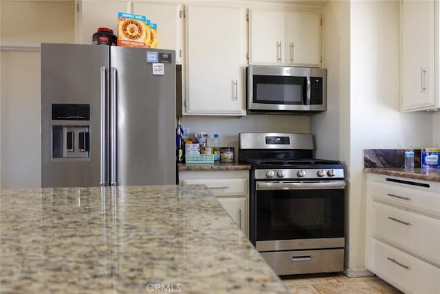 kitchen with appliances with stainless steel finishes, white cabinets, and light stone counters