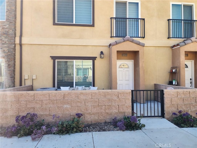 entrance to property featuring a gate, fence, and stucco siding