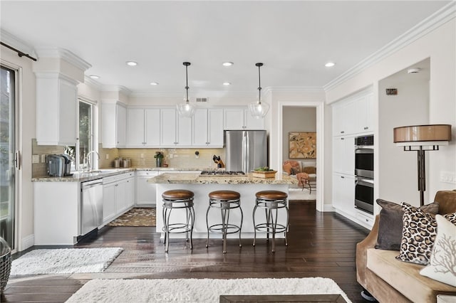 kitchen with light stone counters, appliances with stainless steel finishes, decorative light fixtures, and a center island