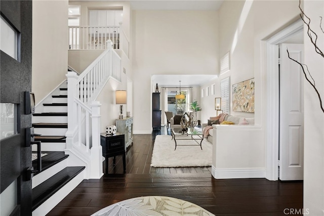 entryway featuring stairway, dark wood finished floors, a towering ceiling, and baseboards