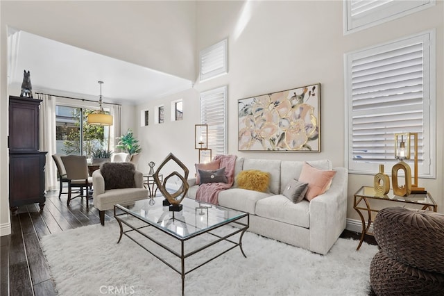 living room with dark wood finished floors, a towering ceiling, and baseboards