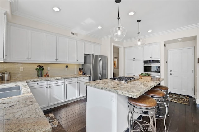 kitchen with visible vents, white cabinets, a center island, hanging light fixtures, and stainless steel appliances