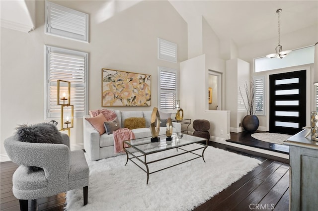 living room with a healthy amount of sunlight, an inviting chandelier, a high ceiling, and dark wood-type flooring