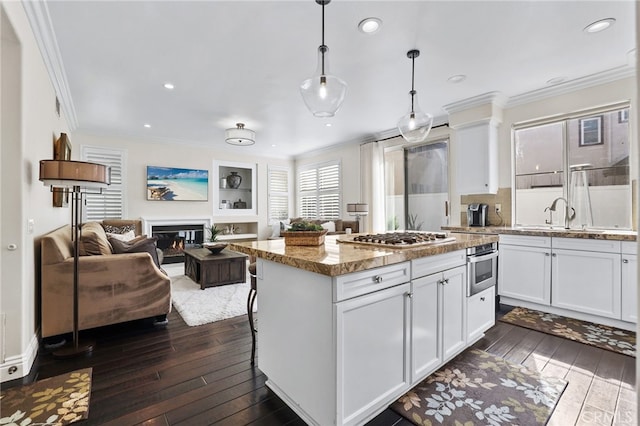 kitchen with white cabinets, appliances with stainless steel finishes, light stone countertops, pendant lighting, and a sink