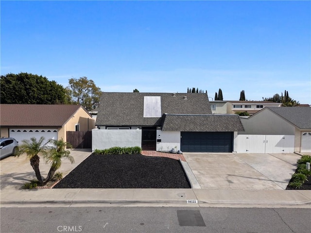 view of front of house featuring concrete driveway, an attached garage, fence, and a gate